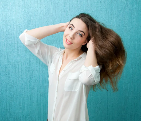 Mujer joven en blusa blanca y maquillaje brillante cerca de la pared azul — Foto de Stock