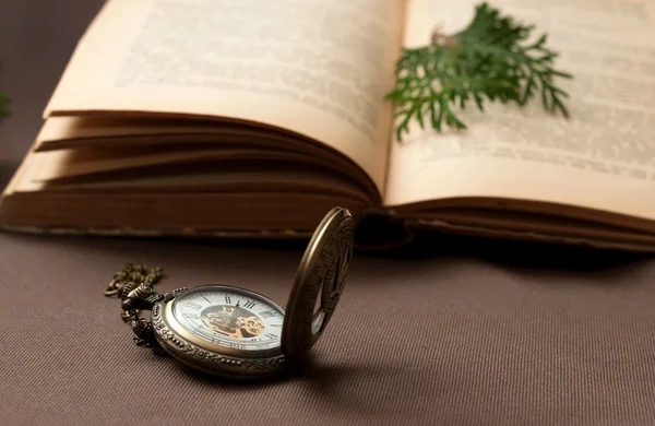 Alte Taschenuhr mit aufgeschlagenem Buch — Stockfoto