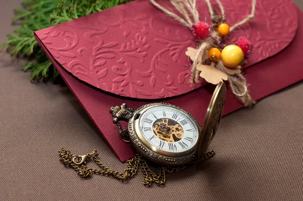 Purple envelope with the old watch on a brown surface