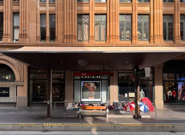 Sydney, Avustralya, Şemsiyeler altında uyuyan insanlar ve şehir merkezindeki Queen Vicotoria Binası 'nda lüks bir perakende mağazasının önünde yatanlar, kentsel evsizliği ve sosyal eşitsizliği vurguluyorlar..