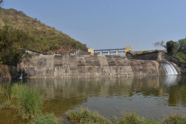 Güneşli bir günde harika görünen eski bir baraj manzarası. Rezervuardan akan suyla birlikte Hint barajı. Bu baraj tüm yıl boyunca ulaşılabilirlik suyuyla ünlüdür.. 