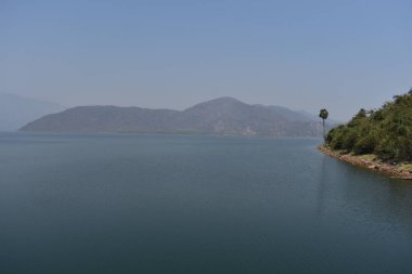 Su deposunun etrafındaki güzel yeşil dağ mavi bulutlu. .