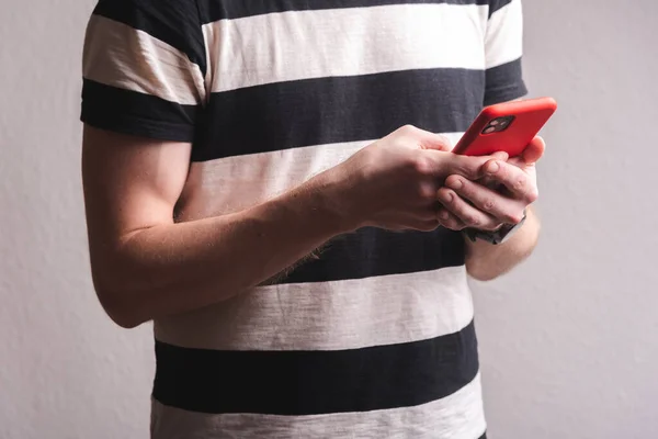 Genç sporcu elinde kırmızı çantalı bir telefon tutuyor.