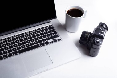 Çalışma masasında bir fincan kahve bilgisayarlı laptop, klasik analog kamera.