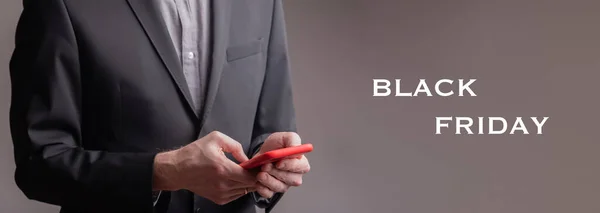 Bir iş adamı kırmızı cep telefonuyla yazı yazıyor - Kara Cuma
