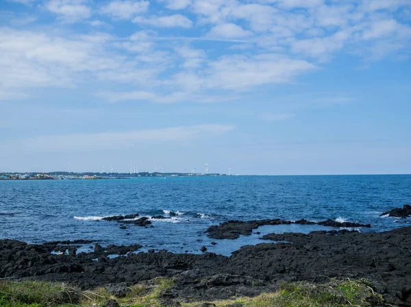 Kore 'deki Jeju adasının siyah kumlu ve gökyüzüyle güzel mavi deniz.