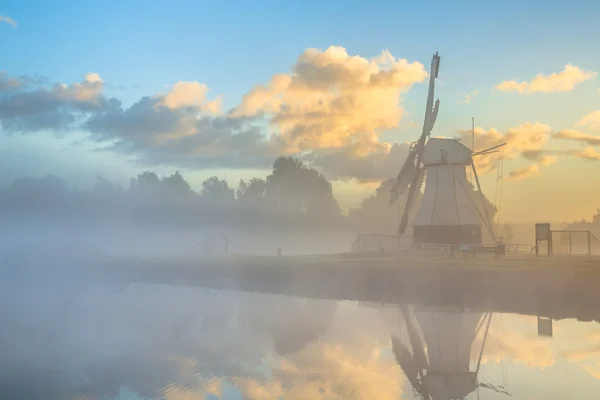 Bílý dřevěný větrný mlýn v ranní mlze — Stock fotografie