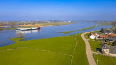 Hollanda, Gelderland 'deki Ravenswaaij köyü yakınlarındaki River Lek hava sahasındaki iç konteynır gemisi.