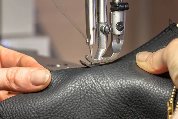 Leather Sewing machine in action in workshop operated with hands working on garment