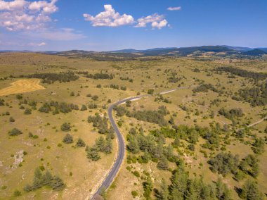 Cevennes Fransa 'sındaki Causse Noir' in kalibreli kireçtaşı karst manzarasından geçen mühürlü viraj yolu.
