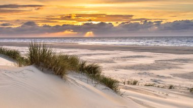 Hollanda 'nın Ameland adasından Kuzey Denizi üzerindeki kum tepesinden gün batımı görüntüsü