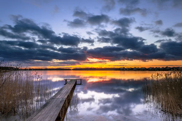 ดวงอาทิตย์ตกสีม่วงเหนือทะเลสาบ Tranquil กับกกและไม้ Jetty — ภาพถ่ายสต็อก