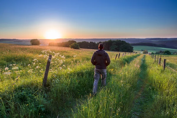 Homem caminhando ao longo da trilha em direção ao pôr do sol — Fotografia de Stock