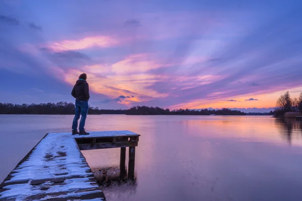 Hombre mirando el atardecer desde un muelle — Foto de Stock