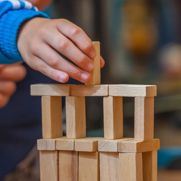 Рука кладет деревянный строительный блок на конструкцию — стоковое фото