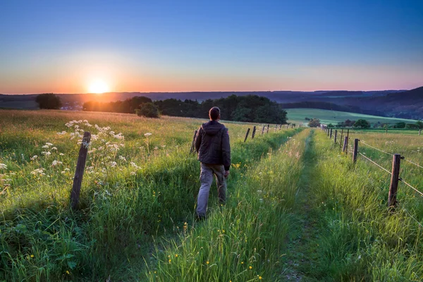 Man går längs vägen mot solnedgången — Stockfoto