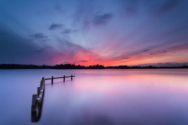Atardecer azul sobre el tranquilo lago con poste de amarre de madera —  Fotos de Stock