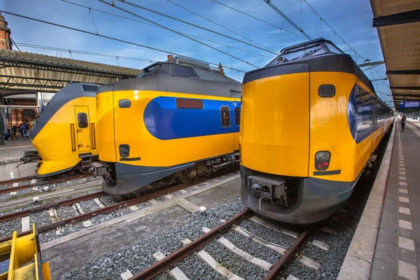 Tre moderna pendlare persontåg väntar vid en historisk sta — Stockfoto
