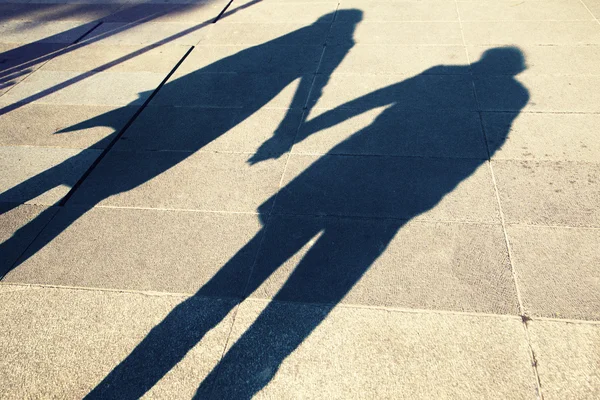 Shadow of two people holding hands on a walk