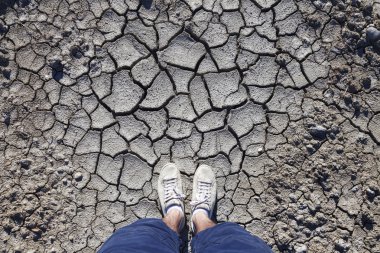 Point of view man standing on cracked soil ground