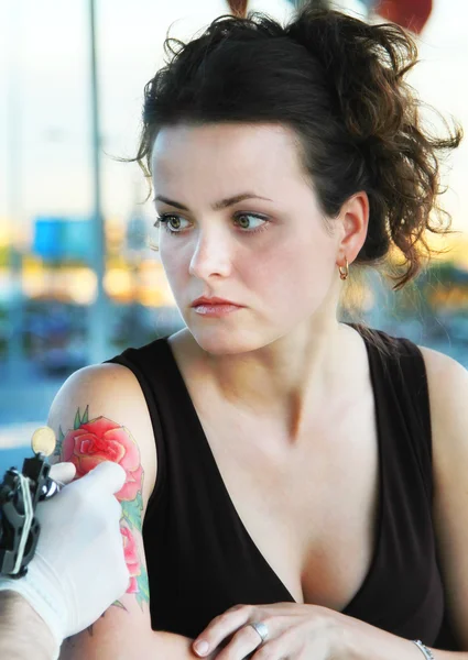 Tatuador mostrando proceso de hacer un tatuaje en joven hermosa mujer — Foto de Stock