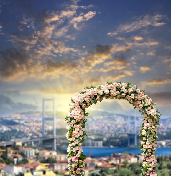 Αψίδα γάμου διακοσμημένη με λουλούδια από τριαντάφυλλα με γέφυρα πάνω στο Βόσπορο στο ηλιοβασίλεμα — Φωτογραφία Αρχείου