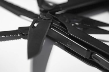 Extreme Macro: Pense, dosya, bıçak, tornavida ve testere ile çoklu aracı açtı. Genişletilmiş araçlar ve pense ile siyah çoklu araç (çoklu araç) beyaz arka planda kapalı. İş ve zanaat kavramı.