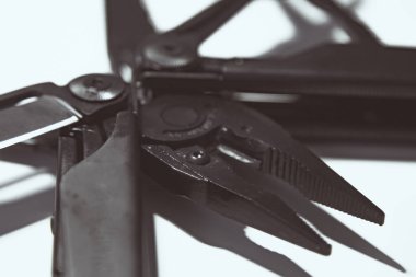 Extreme Macro: Pense, dosya, bıçak, tornavida ve testere ile çoklu aracı açtı. Genişletilmiş araçlar ve pense ile siyah çoklu araç (çoklu araç) beyaz arka planda kapalı. İş ve zanaat kavramı.