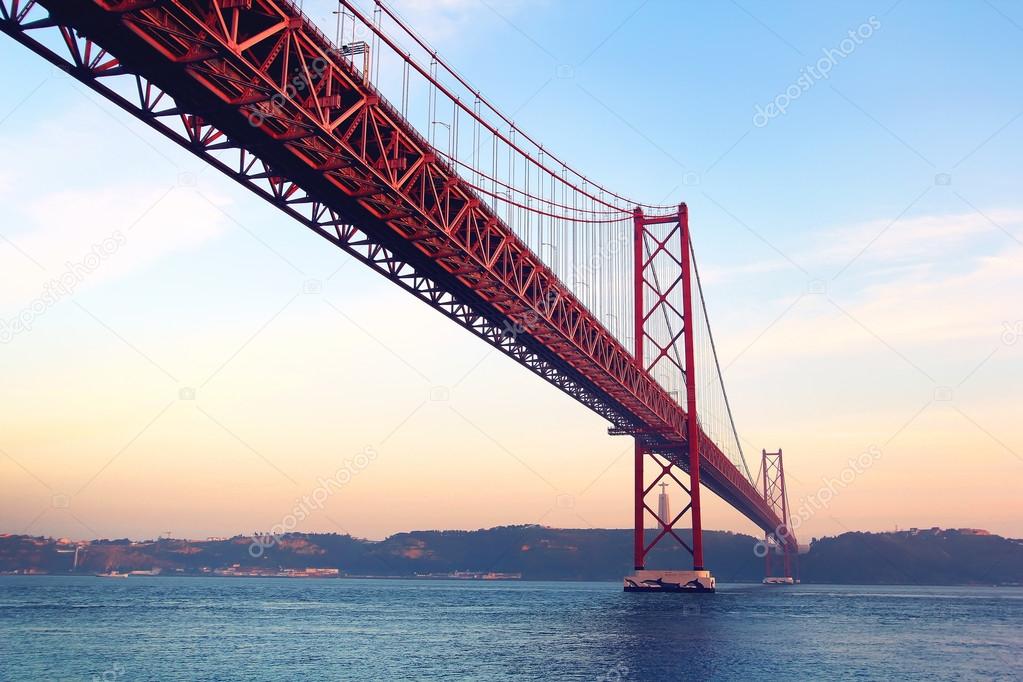 Red bridge at the sunset ( 25 de Abril Bridge and Cristo Rei statue ), Lisbon, Portugal