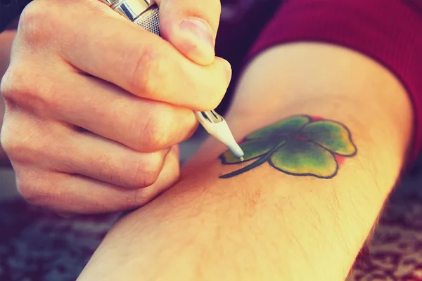 Tatuaje mostrando el proceso de hacer un tatuaje. Diseño del tatuaje en forma de trébol de cuatro hojas — Foto de Stock