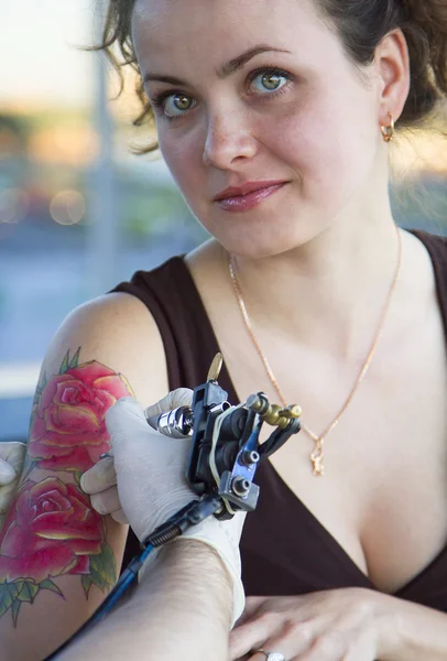 Tatoueur montrant le processus de fabrication d'un tatouage sur jeune belle femme hipster avec la main de cheveux bouclés rouges. Conception de tatouage sous la forme de rose — Photo