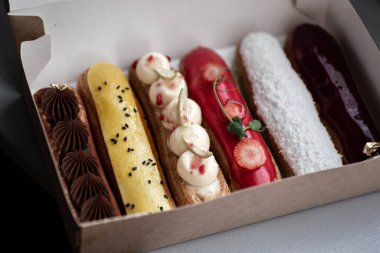 Bir eklem seti. Beyaz arka planda şaşırtıcı derecede taze, ev yapımı ekler var. Lezzetli tatlılar. Lezzetli krema, krema, taze böğürtlen dekor elementleriyle Fransız ekleriName.