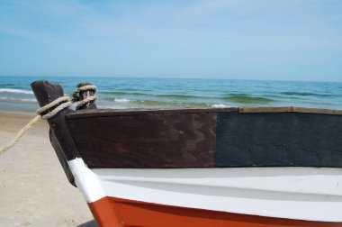 Eski, ahşap bir balıkçı teknesi sahile çekildi, deniz dalgalarının arka planına karşı..