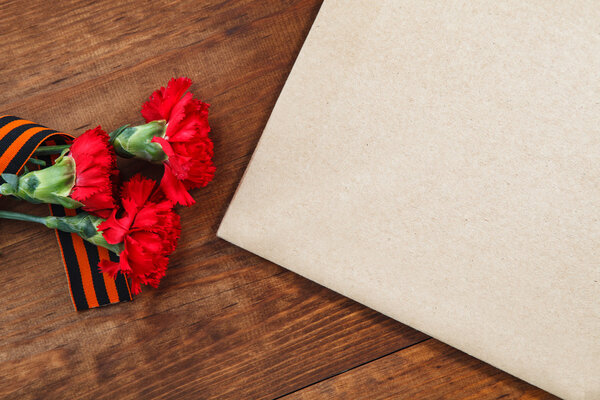 Symbols of Victory in Great Patriotic War three red flower and paper on a table.  selective focus image