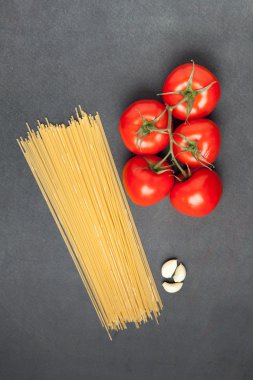 Makarna malzemeler. Domates, spagetti makarna ve sarımsak, karanlık grunge zemin, görünümü top
