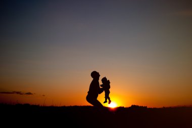 Baba ve çocuk siluetleri günbatımında oynamak. mutlu bir aile