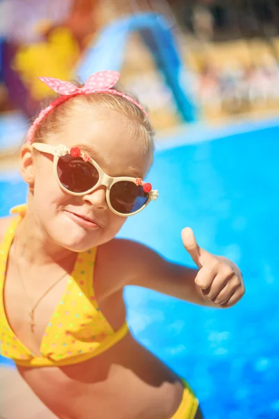 Retrato de una niña feliz parada junto a la piscina. el concepto de vacaciones de verano — Foto de Stock