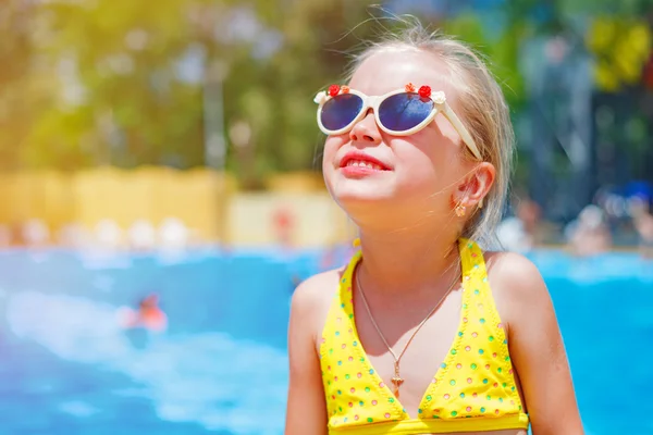 Retrato de un niño en gafas de sol cerca de la piscina en un parque acuático en un día soleado brillante — Foto de Stock