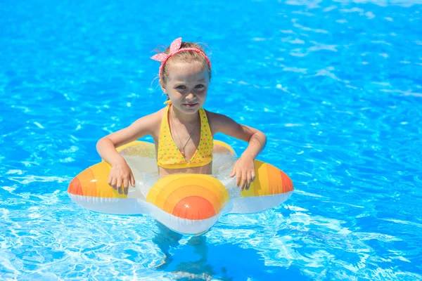 Divertente bambina nuota in una piscina in un salvagente giallo — Foto Stock