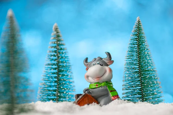 Noel arkaplanda Noel ağaçları ve karlı bir oyuncak boğa var. 2021 yılının sembolü olarak inek. Noel konsepti