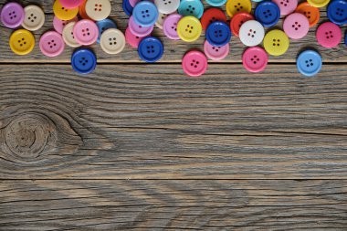 Renkli dikiş düğmeleri ahşap arkaplanda metin için alanı olan bir çerçeve oluşturur.