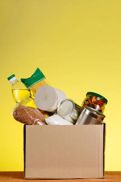 食物捐赠概念 带有食物的捐赠盒 用于黄色回旋的捐赠 在大峡谷病毒大流行的背景下对老年人的援助 垂直射击 免版税图库图片