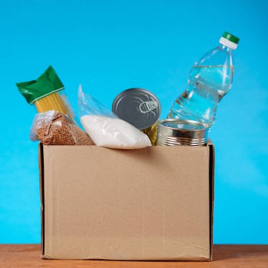 Bağış kutusu mavi arka planda farklı ürünlerle dolu. kare resim