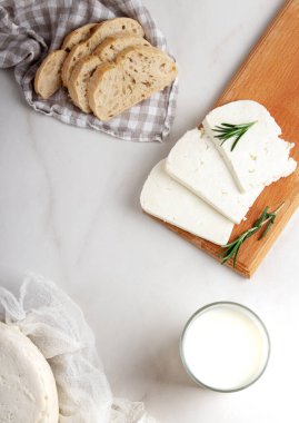 Adighe peyniri, arka planda tahta bir kesme tahtasıyla parçalara ayrılır. Yumuşak keçi peyniri