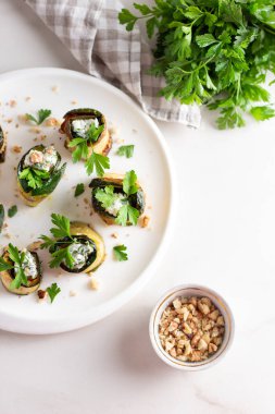 Beyaz tabakta peynirle doldurulmuş kızarmış kabak ruloları. Üst görünüm