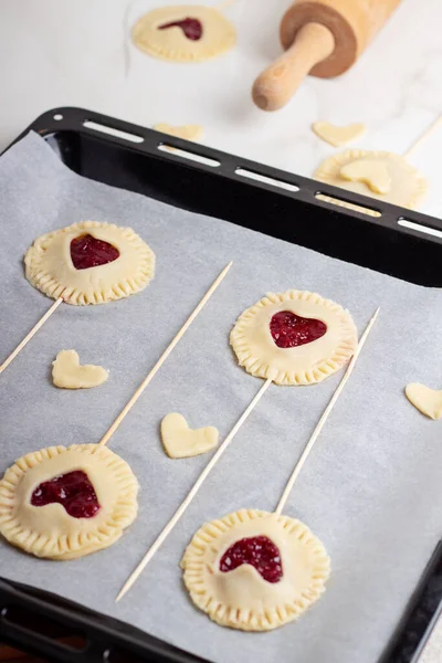 The process of baking small cherry pies on sticks on Valentines Day. Raw cherry pie pops
