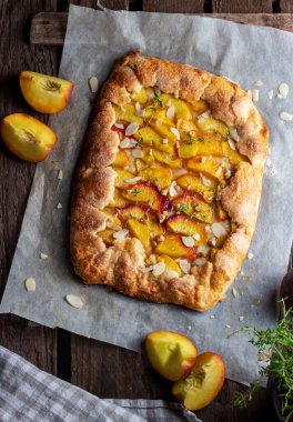 Ahşap arka planda şeftali rengi galet, üst manzara, fotokopi alanı. Yaz yemeği, parşömen kağıdındaki yaz pastası.