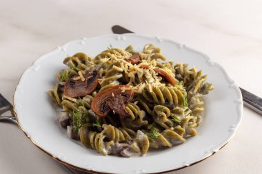 Mantarlı ve peynirli sağlıklı organik ıspanak makarnası beyaz tabakta servis ediliyor.. 