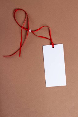 Kırmızı kurdeleli beyaz kağıt etiket ve kahverengi arkaplanda boncuk.