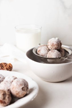 Ev yapımı süzme peynirli çörek topları ve hafif arka planda bir kasede pudra şekeri. Güzel kahvaltı.. 